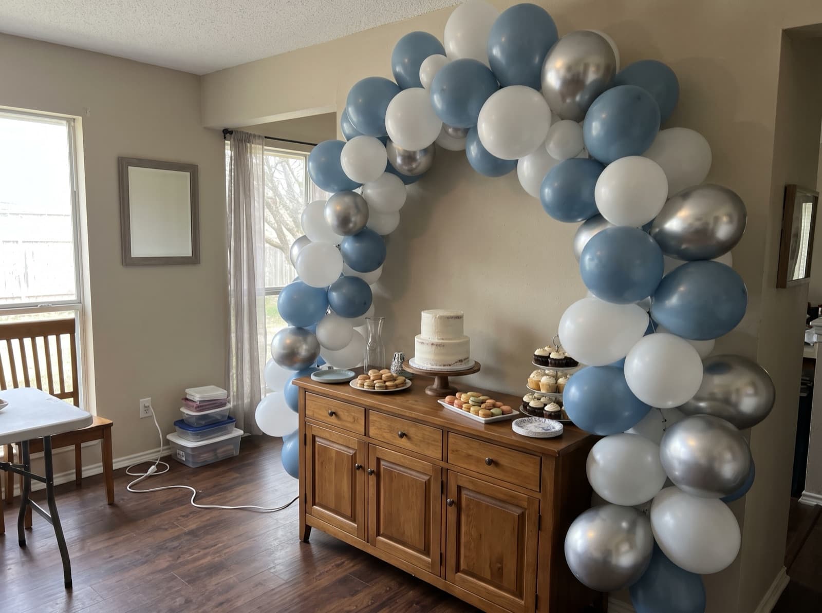 Organic balloon arch in dusty blue, white and silver over a dessert table
